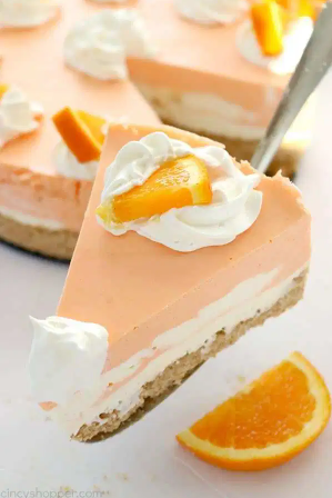 Sliced no baked orange creamsicle cheesecake with whipped  cream and sliced orange on top