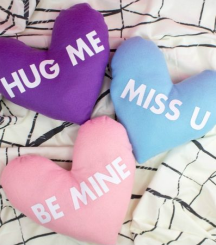 Felt conversation heart pillows with text saying hug me, miss u and be mine