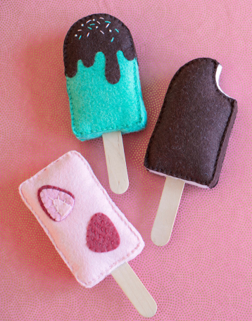 Felt ice cream bars one looks like a chocolate ice cream bar with a bite on it, second looks like a pink strawberry flavor ice cream bar an the last one is a color mint green ice cream bar with a chocolate syrup on top and sprinkle on it.