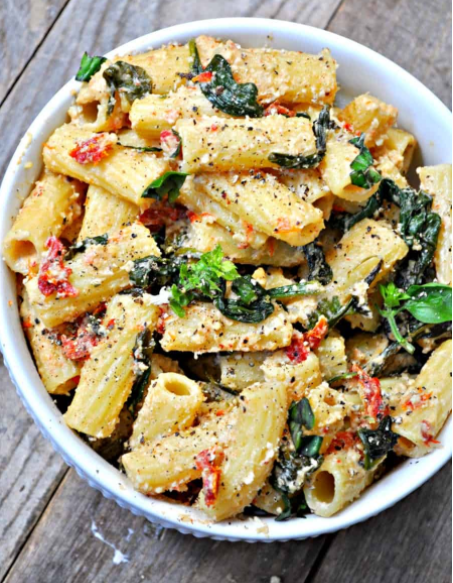 A bowl of vegan Tuscan rigatoni with toppings of fresh basil and black pepper