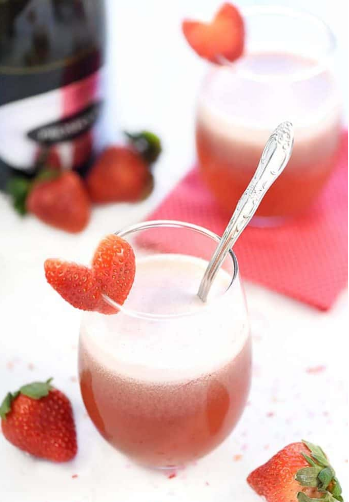 Sparkling strawberry floats on a glass with a heart shaped fresh strawberry 