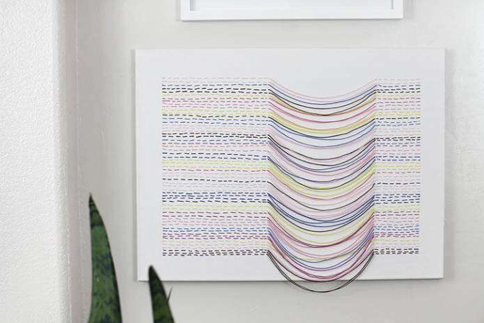 Embroidered canvas wall art that looks like a stitch with cool draped effect