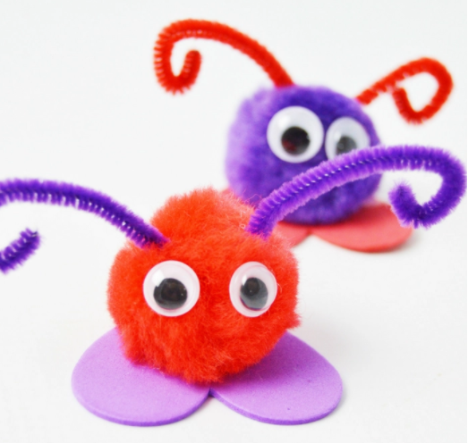 Valentine's day bug craft made from pompoms one is a color red with a googly eyes sitting on a purple foam heart shape the other one is a color blue with a googly eyes sitting on a red foam heart shape