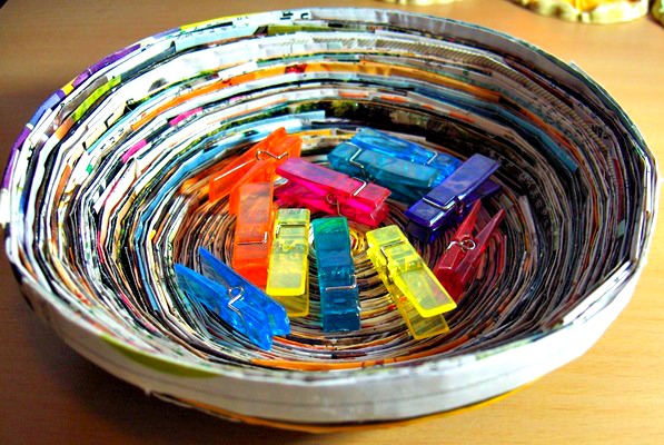 A beautiful bowl made from an old magazines with some paper clips on it
