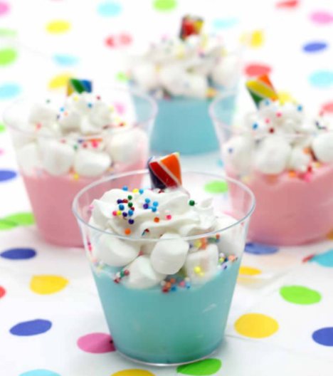 Unicorn pudding cups with marshmallow and whip cream on top sprinkled with rainbow sprinkles