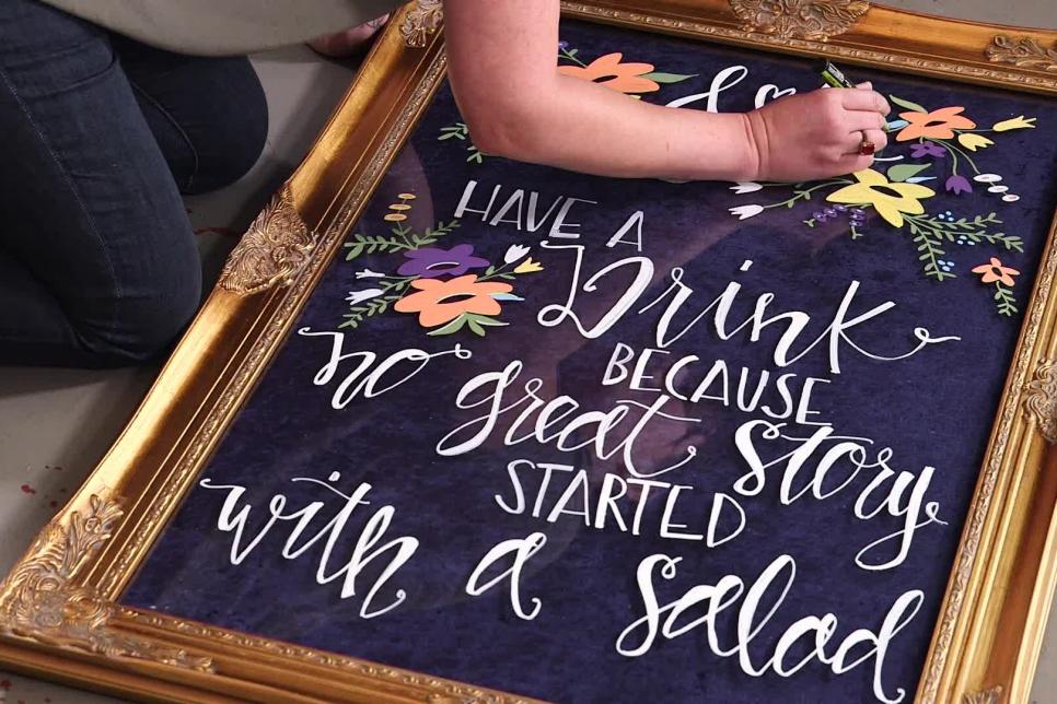 placa de casamento escrita à mão com lindas flores aleatórias e texto dizendo Beba porque nenhuma boa história começou com uma salada