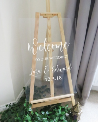 Sinal de boas-vindas do casamento feito de uma placa de vidro com texto dizendo bem-vindo ao nosso casamento Lara e Edward 12.3.18