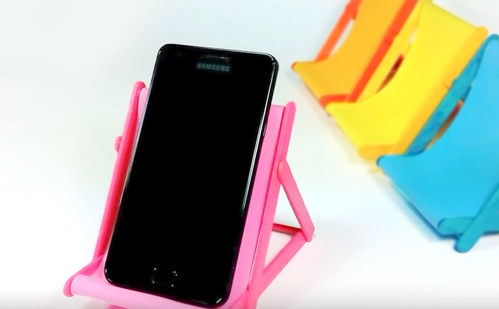 A cute and colorful homemade phone holder and lawn chair made of popsicle sticks 