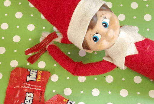 elf on the shelf on a candy jar with delicious sweets 