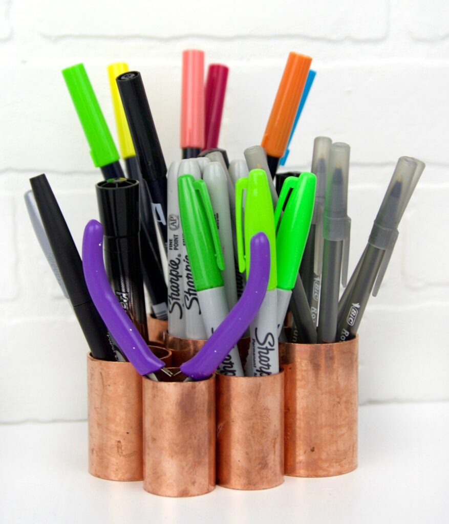 Copper pipe desk organizer with different kind of pens on it