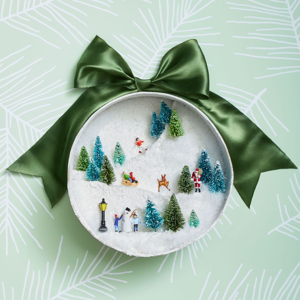 Transform a round gift box into a snowy sled scene with styrofoam and figurines.