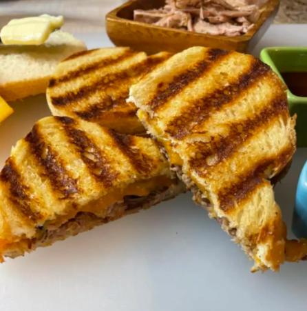 Sweet and tender pulled pork with cheddar cheese between two slices of grilled ciabatta bread