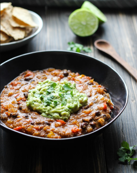 A bowl of flavorful Mexican Ranchero Amaranth Stew garnished with avocado and chopped cilantro