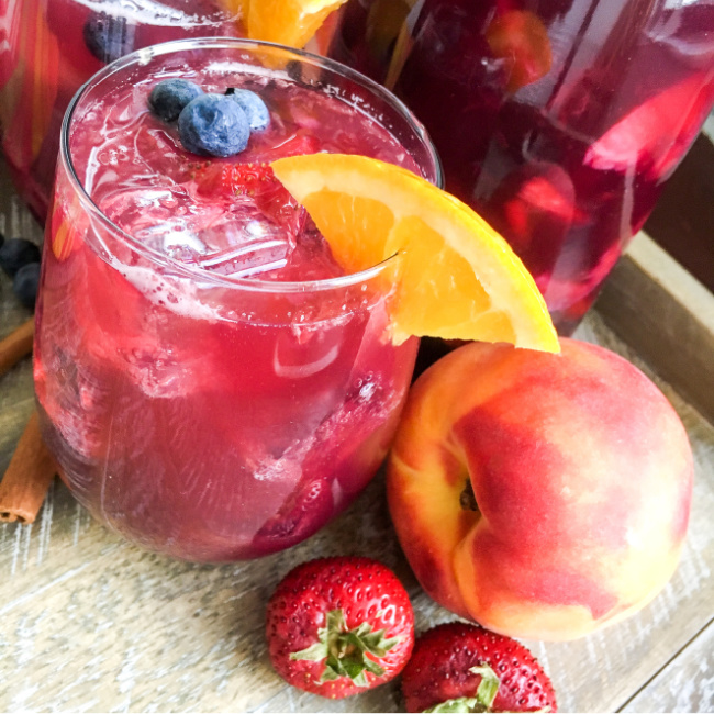 Berry Peach Sparkling Sangria garnish with an orange wedge perfect for summer