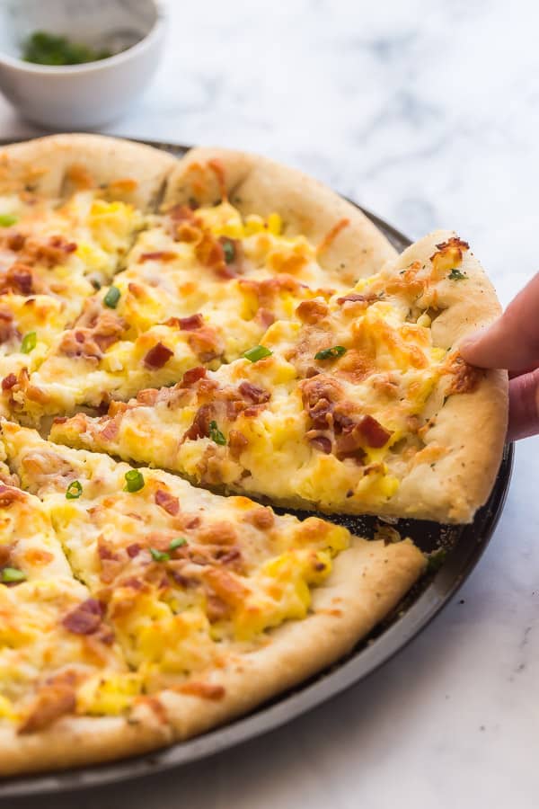 Breakfast Pizza that has a lot of scrambled eggs, crispy bacon and cheese