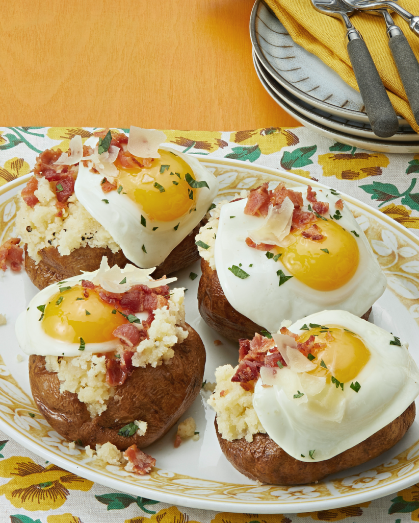 Carbonara baked potatoes top with fried egg, bacon and shaved parmesan and parsley