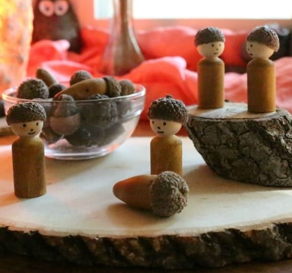 cute little acorn peg dolls made with acorn caps, wooden peg dolls, and a touch of watercolor paint.