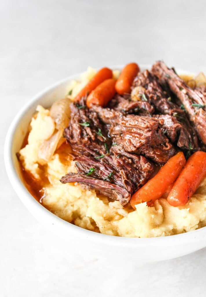 Slow cooker garlic herb pot roast served over mashed potatoes the ultimate Fall comfort food meal