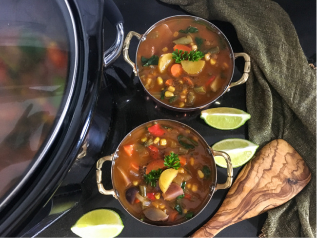 Slow cooker vegan vegetable soup garnished with lime slices and fresh parsley
