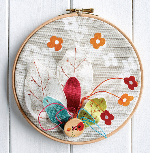 Embroider hoop wal; art that has flowers, leaves and a button design on it
