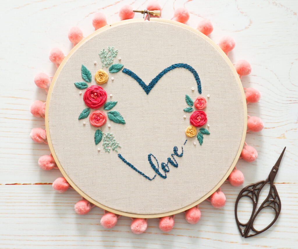 Floral Embroidery Hoop Art it has beautiful flowers and a text saying love 