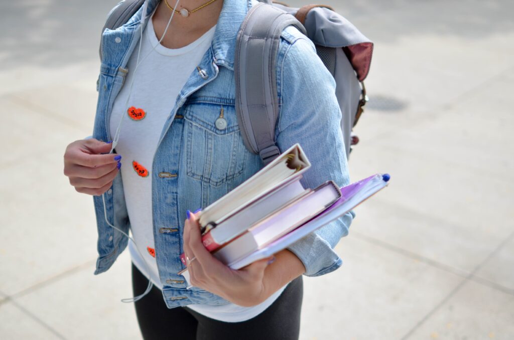 person holding books and backpack